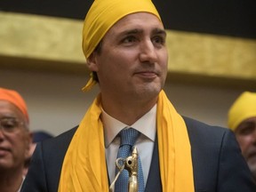 Prime Minister Justin Trudeau stands after having a scarf placed on him and being presented with a gift after speaking at the Khalsa Diwan Society Sikh Temple before marching in the Vaisakhi parade, in Vancouver on Saturday April 13, 2019 (The Canadian Press)
