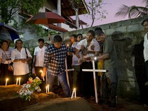 Relatives place flowers after the April 22, 2019 burial of three victims of the same family, who died in an Easter Sunday bomb blast at St. Sebastian Church in Negombo, Sri Lanka. (AP Photo/Gemunu Amarasinghe)