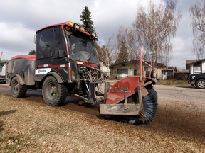 A worker uses a sweeper to clean a sidewalk during a press conference near 36 Street and 104 Avenue in Edmonton, on Friday, April 12, 2019.