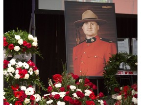 A photo of slain RCMP Const. David Wynn stands amongst flowers during his funeral procession in St. Albert, Alta., on Jan. 26, 2015. Wynn died four days after he and Aux. Const. Derek Bond were shot by Shawn Rehn in St. Albert, Alta, on Jan. 17, 2015.