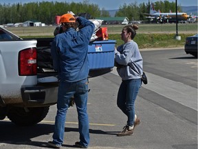 Some of the 4000 High Level evacuees from the Chuckegg Creek fire, like Mathew Blaney and Courtanne Biodiversity loading up possessions which they managed to get from there homes, in the parking lot of the Legacy Centre, as water bombers (back) prepare for take-off from the airport in Slave Lake, May 21, 2019.