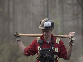 A firefighter carries an axe to battle northwest Alberta wildfires near the town of High Level on Friday, May 24, 2019. About 5,000 people in High Level and surrounding communities have been out of their homes since the long weekend, as the Chuckegg Creek fire rages three kilometres outside the town.