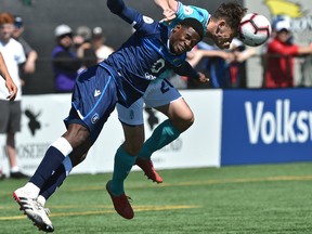 FC Edmonton's Kareem Moses (12) and Pacific FC's Emile Legault (20) go after the header during Canadian Premier League action at their home opener at Clarke Stadium in Edmonton, May 12, 2019.
