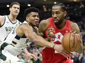 Bucks forward Giannis Antetokounmpo (centre) defends as Raptors forward Kawhi Leonard (right) controls the ball during second half action in Game 5 of the NBA Eastern Conference final in Milwaukee on Thursday, May 23, 2019.