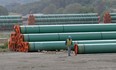 A workman walks past steel pipe to be used in the oil pipeline construction of Trans Mountain Expansion Project at a stockpile site in Kamloops, British Columbia.