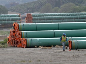 A workman walks past steel pipe to be used in the oil pipeline construction of Trans Mountain Expansion Project at a stockpile site in Kamloops, British Columbia.