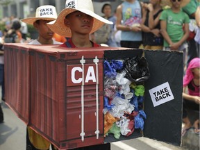 In this May 7, 2015, file photo, Filipino environmental activists wear mock containers filled with garbage to symbolize the 50 containers of waste that were shipped from Canada to the Philippines two years ago, as they hold a protest outside the Canadian embassy at the financial district of Makati, south of Manila, Philippines.