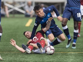 Yong-Chan Son of FC Edmonton, falls to the ground with Marco Bustos of Valour FC at Clarke Field in Edmonton on June 2, 2019. Photo by Shaughn Butts / Postmedia