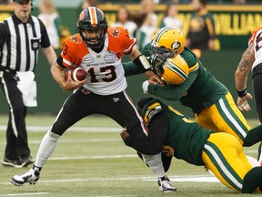 Edmonton Eskimos' Almondo Sewell (90) and Martese Jackson (30) tackle BC Lions' quarterback Mike Reilly (13) during a CFL football game at Commonwealth Stadium in Edmonton, on Friday, June 21, 2019.