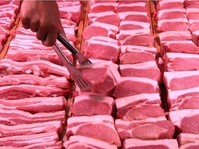 A staff member lifts a pork slice with tongs at a supermarket in Handan, Hebei province, China June 12, 2019.