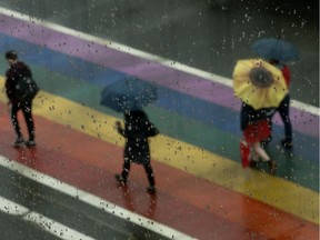 Pedestrians make their way through the rain near 109 Street and 104 Avenue, in Edmonton Thursday June 20, 2019. The crosswalk had been painted for Pride Month.