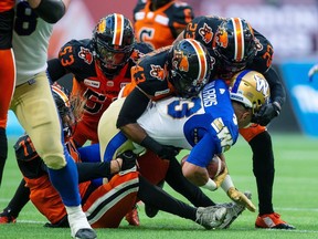 Winnipeg Blue Bombers running back Andrew Harris (33) is tackled by B.C. Lions defensive back Dominique Termansen (43) during the first half of the Lions' home opener on Saturday.