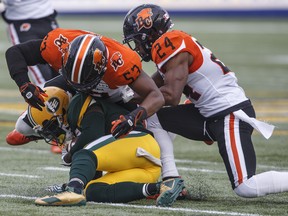 B.C. Lions Jordan Herdman-Reed (53) and Chris Edwards (24) tackle Edmonton Eskimos receiver Natey Adjei (3) in Edmonton on Friday, June 21, 2019.