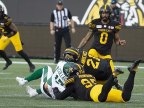 Saskatchewan Roughriders quarterback Zach Collaros, bottom left, is hit late by Hamilton Tiger-Cats linebacker Simoni Lawrence, 21, early in Thursday's CFL game at Tim Hortons Field.