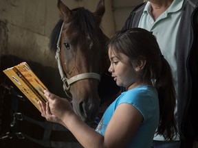Hannah Silva Koch reads to Tenor, a five-year-old gelding, when Grade 1 and 2 students from Delwood School visited the Arabian Horse Reading Literacy Project in Ardrossan to participate in equine assisted learning on Friday, June 14, 2019.