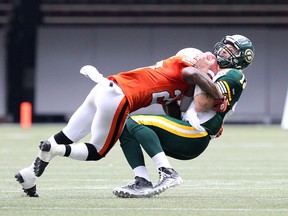 B.C. Lions’ Josh Johnson (top) tackles  Edmonton Eskimos  quarterback Mike Reilly at BC Place in Vancouver, B.C. in this photo taken on June 28, 2014.