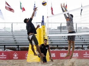 Members of Team Japan (left) and Team Canada practice in the pouring rain during the FIVB Beach Volleyball World Tour, in Edmonton Wednesday July 17, 2019.