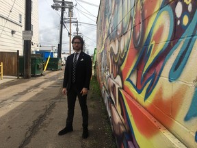 Brandon Bernhardt stands next to the mural Derks Formals commissioned to deter graffiti vandals from defacing their store.