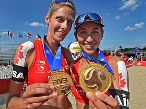 Canadians Sarah Pavan, left, and Melissa Humana-Paredes holdup their gold medals after winning in the final of FIVB Beach Volleyball World Tour with 90 teams representing 25 countries at the Northlands racetrack in Edmonton, Sunday, July 21, 2019.