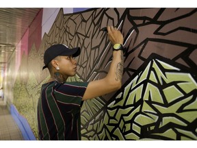 Artist Jonathon Cardinal works on a new mural on the Valley Line LRT between Churchill LRT station and Edmonton City Centre in Edmonton on Tuesday, July 23, 2019.