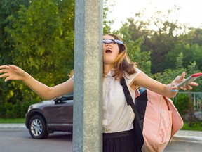 Portrait of young inattentive girl, distracted by mobile phone. Girl crashed into street post, dropped phone