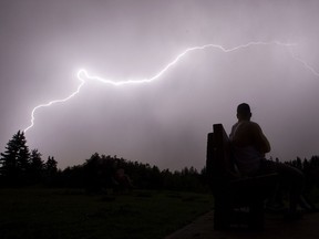 A man sits on a bench and watches the lightning near Saskatchewan Drive and 119 Street, in Edmonton Alta. on Monday June 6, 2016.