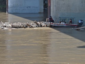 The fire department rescue boat trying dismantle a log jam of wood debris on one of the Quesnell Bridge piers in Edmonton, July 12, 2019. Ed Kaiser/Postmedia