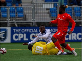 Forge FC goalkeeper Quillan Roberts makes a save on FC Edmonton forward Oumar Diouck while Forge FC defender Dominic Samuel looks on at Clarke Field on Saturday, July 27, 2019.