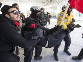 A woman against Islamophobia braces herself against a wall before police take her away. Demonstrators protest against Islamophobia and for free speech clash at City Hall in Toronto, Ont. on Saturday March 4, 2017.