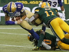 Winnipeg Blue Bombers quarterback Chris Streveler is hauled down by Edmonton Eskimos Larry Dean (right) and Don Unamba (bottom) during Canadian Football League game action in Edmonton on Friday August 23, 2019.