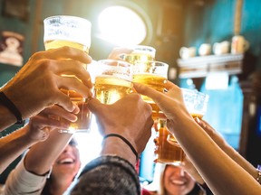 Group of happy friends drinking and toasting beer at brewery bar restaurant - Friendship concept with young people having fun together at cool vintage pub - Focus on middle pint glass - High iso image