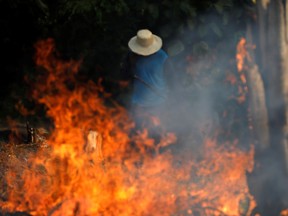 A man works in a burning tract of Amazon jungle as it is being cleared by loggers and farmers in Iranduba, Amazonas state, Brazil August 20, 2019.