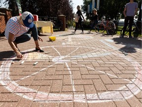 Sarah Hoyles with Paths for People chalks an art bike into the brick at Const. Ezio Faraone Park during High Level Line Day in Edmonton, on Saturday, Sept. 7, 2019.