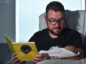 Rob Braund holds his two-day-old daughter Lily while reading a book that came in the Welcome Baby early literacy program package that has been expanded to the Neonatal intensive care unit at the Misericordia Hospital in Edmonton, Sept. 9, 2019. Ed Kaiser/Postmedia