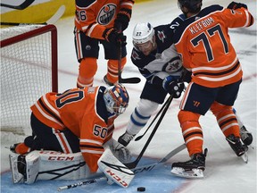 Winnipeg Jets centre Mark Letestu pokes the puck from underneath Edmonton Oilers goalie Stuart Skinner as defenceman Oscar Klefbom tries to tie him up during NHL pre-season action on Sept. 16, 2019, at Rogers Place.