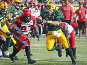 Edmonton Eskimos quarterback Trevor Harris is chased down by Calgary Stampeders defensive lineman Derek Wigan (97) during a Canadian Football League game at Commonwealth Stadium.