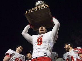 Laval University Rouge et Or's Mathieu Betts raises the trophy as they celebrate victory against Western University Mustang at the Vanier Cup final in Quebec City, Saturday, Nov. 24, 2018.
