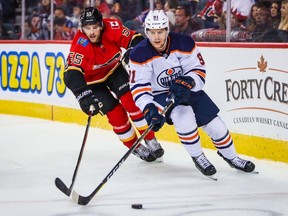 Edmonton Oilers center Gaetan Haas (91) and Calgary Flames defenseman Noah Hanifin (55) battle for the puck during the second period at Scotiabank Saddledome.