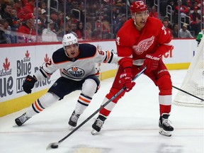 Madison Bowey #74 of the Detroit Red Wings looks to pass the puck away from Patrick Russell #52 of the Edmonton Oilers during the first period at Little Caesars Arena on October 29, 2019 in Detroit, Michigan.