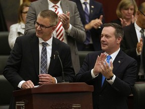 Alberta Finance Minister Travis Toews, left, is applauded by Alberta Premier Jason Kenney after Toews delivered his budget speech at the Alberta legislature in Edmonton on Thursday, Oct. 24, 2019.