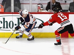Connor McDavid #97 of the Edmonton Oilers and Jonathan Toews #19 of the Chicago Blackhawks chase the puck at the United Center on January 7, 2018 in Chicago, Illinois. The Blackhawks defeated the Oilers 4-1.