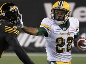 Edmonton Eskimos running back Christion Jones (22) gets a hand into the face if Hamilton Tiger Cats linebacker Nick Shortill (23) during second half CFL football game action in Hamilton, Ont., Friday, Oct. 4, 2019.