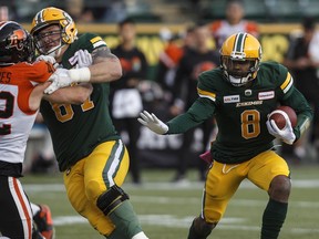 Edmonton Eskimos' Troy Williams (8) runs the ball as B.C. Lions' Kevin Haynes (42) and teammate Colin Kelly (67) battle during first half CFL action in Edmonton on Saturday, Oct. 12, 2019.