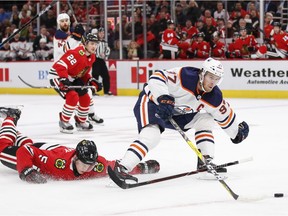 Edmonton Oilers centre Connor McDavid, right, attempts to control the puck as Chicago Blackhawks defenceman Connor Murphy defends at United Center on Oct. 14, 2019.