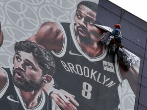 A worker removes a promotional banner from a building for the NBA preseason game in China between the Brooklyn Nets and the Los Angeles Lakers in Shanghai on October 9, 2019. (HECTOR RETAMAL/AFP via Getty Images)
