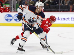 Detroit Red Wings left wing Taro Hirose (67) tries to knock the puck from Edmonton Oilers center Connor McDavid (97) Tuesday, Oct. 29, 2019, in Detroit.