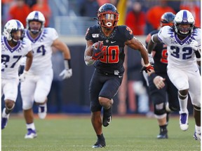 Running back Chuba Hubbard, #30 of the Oklahoma State Cowboys, breaks loose on a 62-yard run to score a touchdown against safety Ar'Darius Washington #27 and defensive end Ochaun Mathis #32 of the TCU Horned Frogs on Nov. 2, 2019 at Boone Pickens Stadium in Stillwater, Okla. OSU won 34-27.