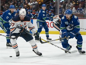 Connor McDavid #97 of the Edmonton Oilers tries to get past Jordie Benn #4 and Christopher Tanev #8 of the Vancouver Canucks during NHL action at Rogers Arena on Sunday, Dec. 1, 2019 in Vancouver.