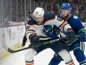 Oscar Fantenberg #5 of the Vancouver Canucks checks Patrick Russell #52 of the Edmonton Oilers while battling for the loose puck during NHL action at Rogers Arena on December 1, 2019 in Vancouver. Rich Lam / Getty Images