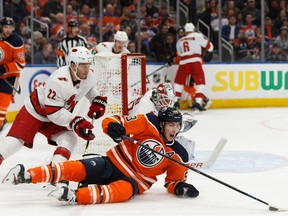 Edmonton Oilers' Ryan Nugent-Hopkins (93) is tripped by Carolina Hurricanes' Brett Pesce (22) during the third period of a NHL hockey game at Rogers Place in Edmonton, on Tuesday, Dec. 10, 2019.